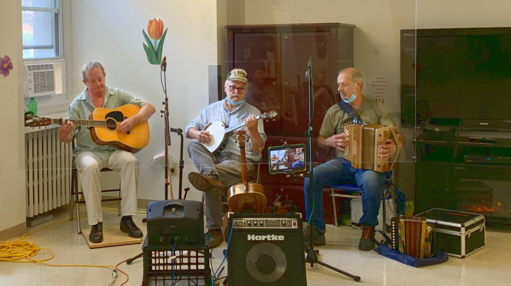 Jean Cantin, Claude Méthé et Michel Leblanc avec leur guitare, banjo et accordéon en jouant dans un foyer de personnes âgées