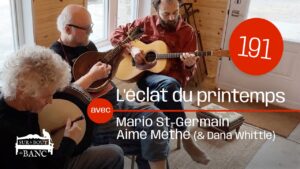 Trois musiciens jouent bodhran, mandoline et guitare ténor dans une entrée illuminée par le soleil.