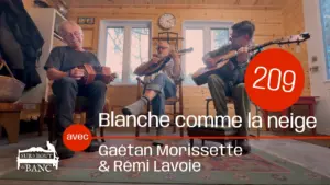 Trois hommes jouent de la musique traditionnelle dans une entrée de maison, sur concertina, mandoline et guitare.