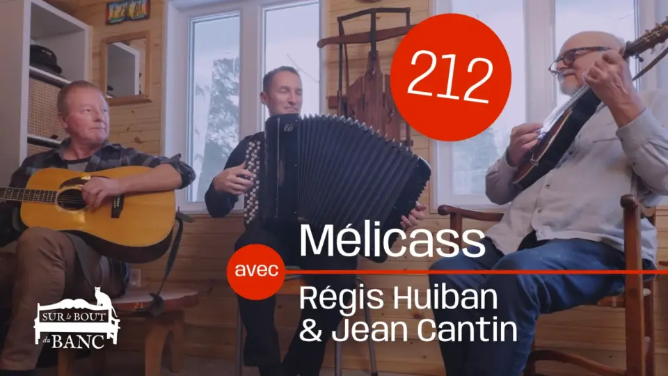 Trois hommes jouent guitare, accordéon et mandola dans une entrée en hiver.