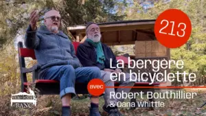 Deux hommes chantent sur un banc rouge à l'automne, entourés de feuilles et arbres