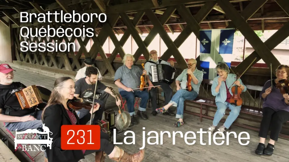 Un groupe de musicien(ne)s jouent violons, accordéons, banjo dans un pont couvert devant un drapeau québécois.