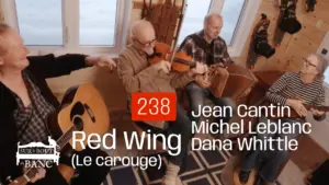 Trois hommes et une femme jouent guitare, violon, accordéon et bass dans une entrée de maison.