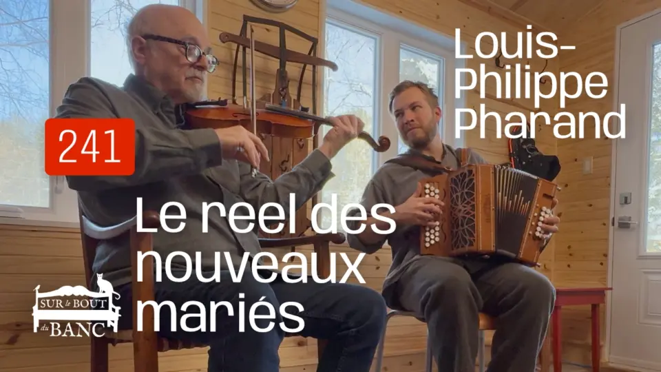 Deux hommes jouent violon et accordéon dans une entrée de maison.