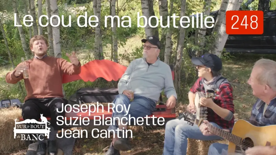 Deux homme sur un banc rouge, chantent; une femme et un homme jouent banjo et guitar en accompagniment, dehors à l'automne