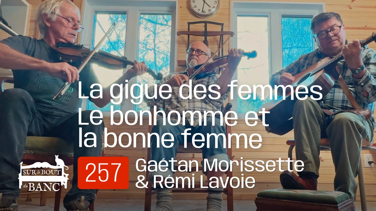 Trois hommes jouent violons et guitare dans une entrée de maison